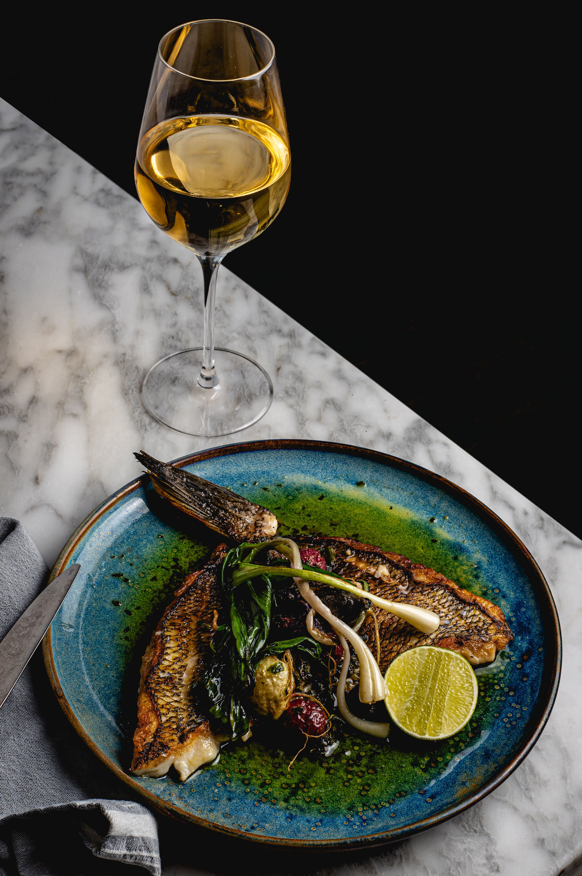 Black Bass on a Blue Plate with a Glass of White Wine