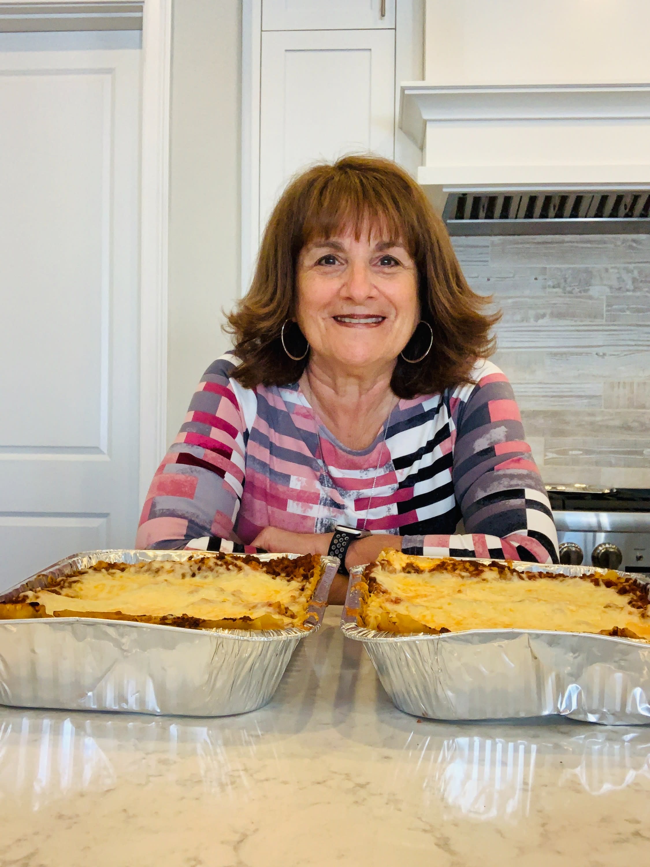 A photo of Lynn Hirsch, Outreach Director with Lasagna Love, and two lasagnas