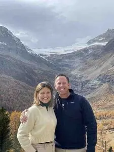 couple smiling for camera with mountains in background