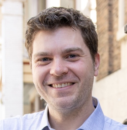 A person smiling at the camera  Description automatically generated