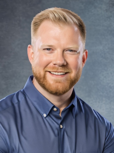 A person with a beard and mustache wearing a blue shirt  Description automatically generated