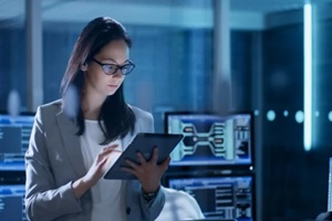 young female government employee wearing glasses uses tablet in system control center