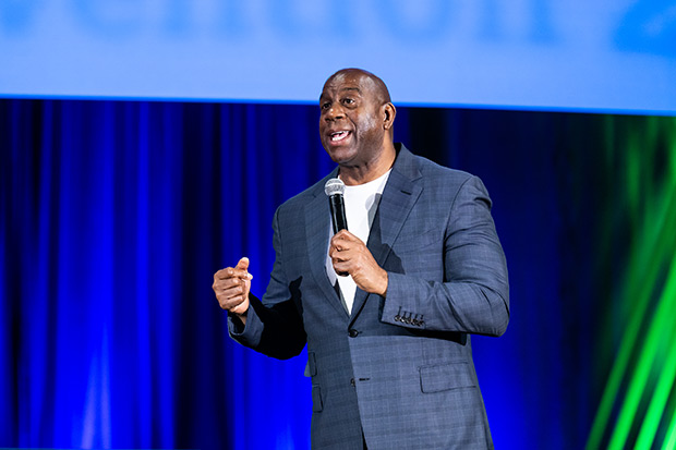 A man in a blue suit speaks into a microphone during a presentation