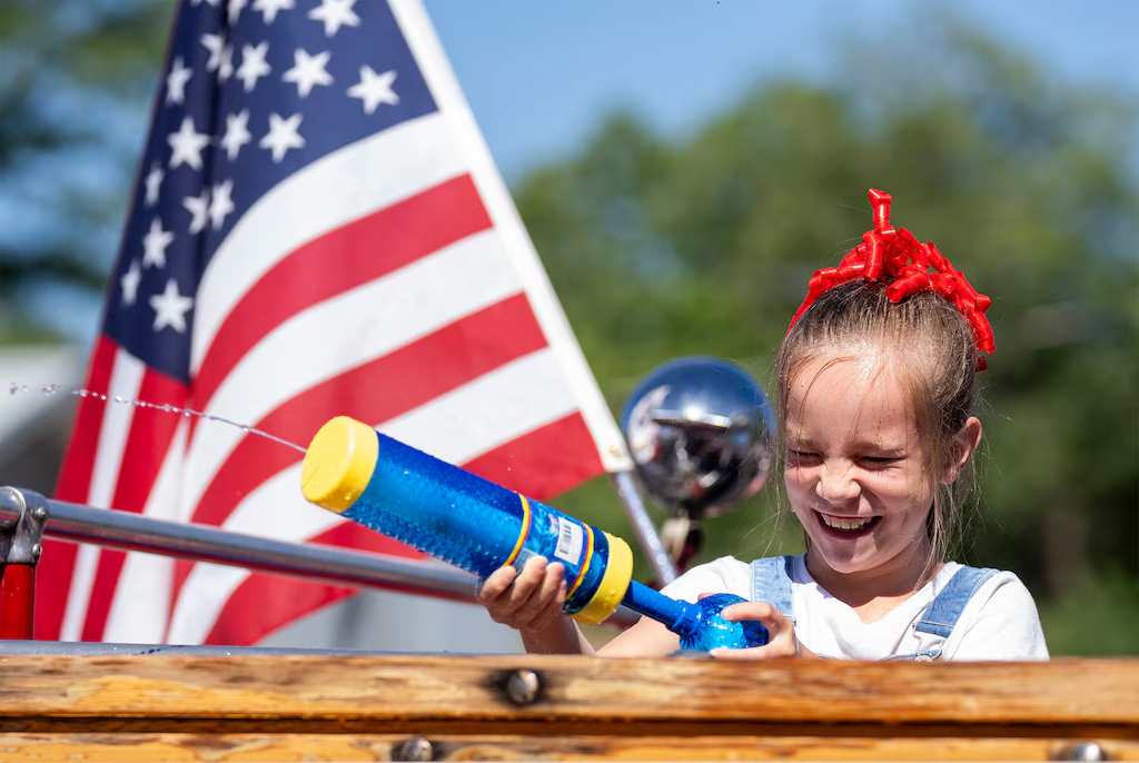 (Rick Egan | The Salt Lake Tribune) Maggie Hopkin dodges a stream of water as she fires back into the crowd from a fire engine during an Independence Day parade in Morgan on Thursday, July 4, 2024.