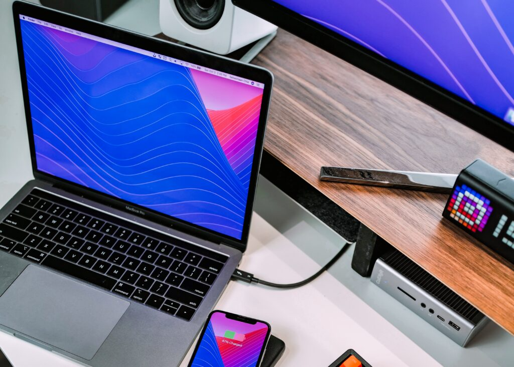 Electronics including a laptop, monitor, phone, and speaker.