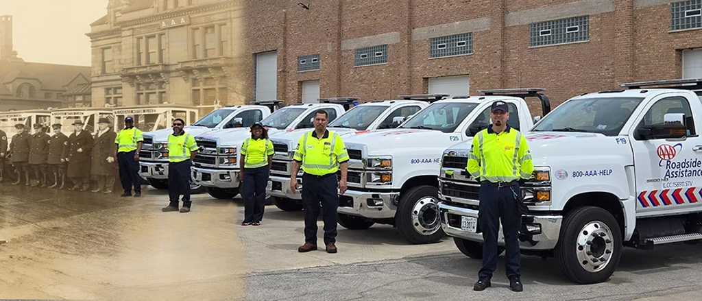 AAA technicians in uniform stand beside a fleet of branded roadside assistance trucks, ready for service.