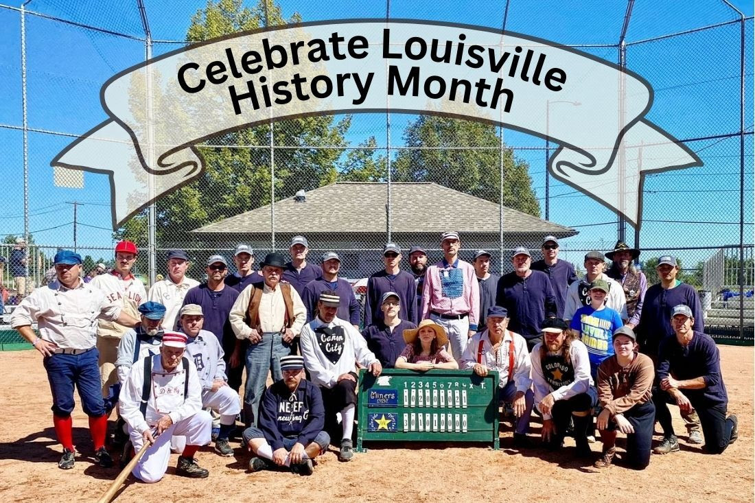 Score keepers and members of Vintage Base Ball teams pose together for a photo around a score board.