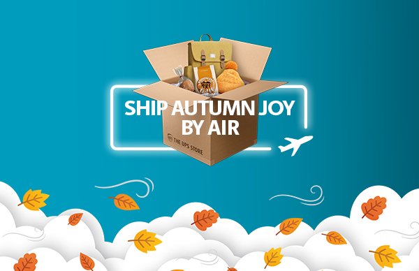 A box of fall themed goods like a beanie, pumpkin spice cookies and backpack packed in a box with the words "Ship Autumn Joy by Air".