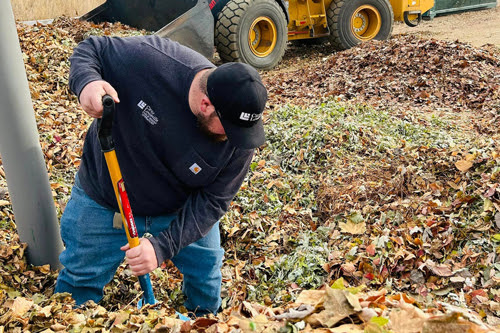 Photo of city worker with shovel in a pile of leaves