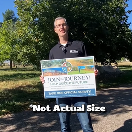 Parks Manager, Bryon standing with a giant Join the Journey Postcard