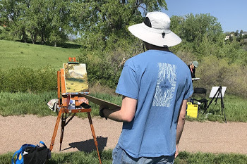 person painting a open space on a easel 