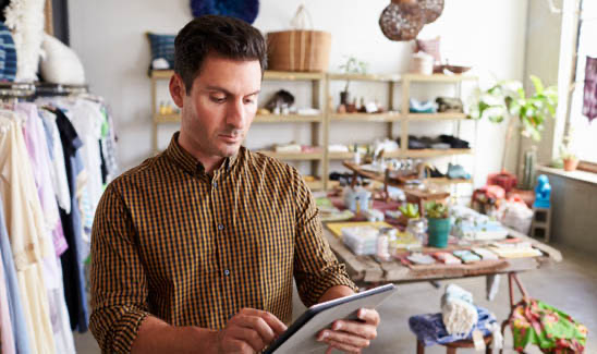 Small business clothing shop owner on tablet in store