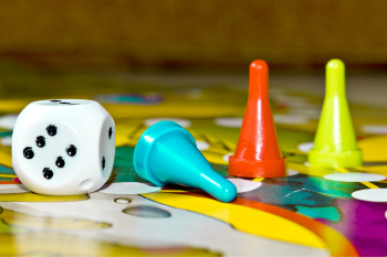 A colorful board game featuring dice and various game pieces arranged on the playing surface.