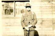 World War I soldier in front of a wooden structure