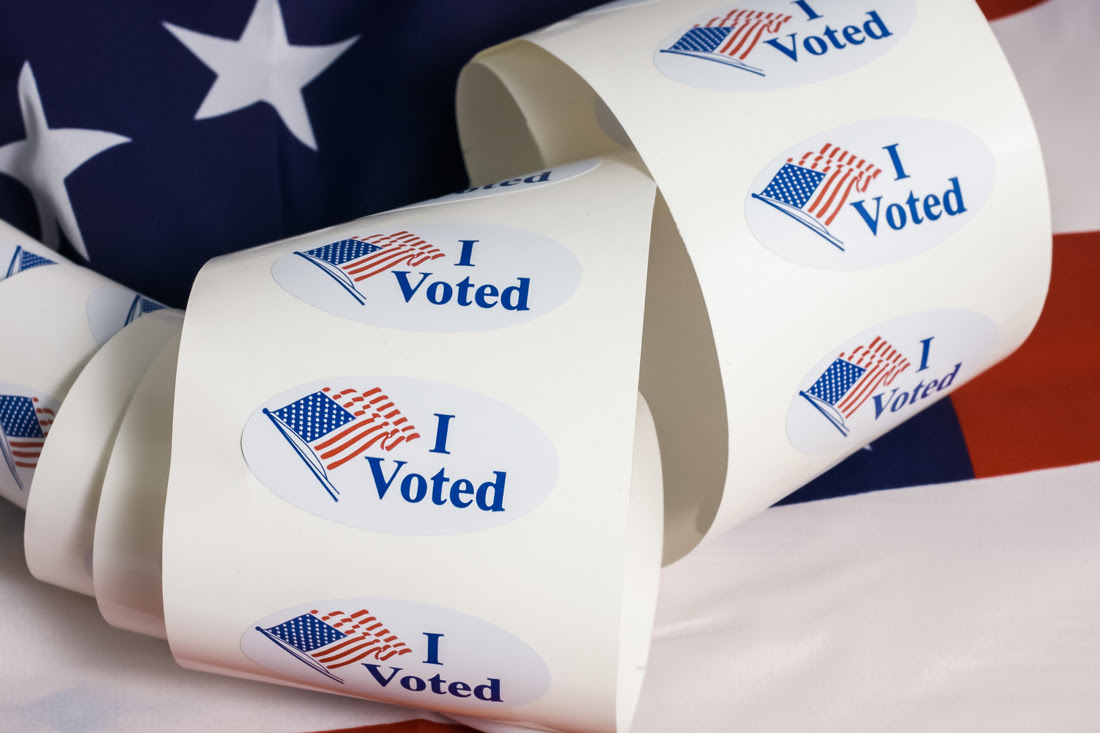 Roll of I Voted stickers atop an American flag, election