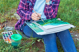 Young person sitting on grass painting