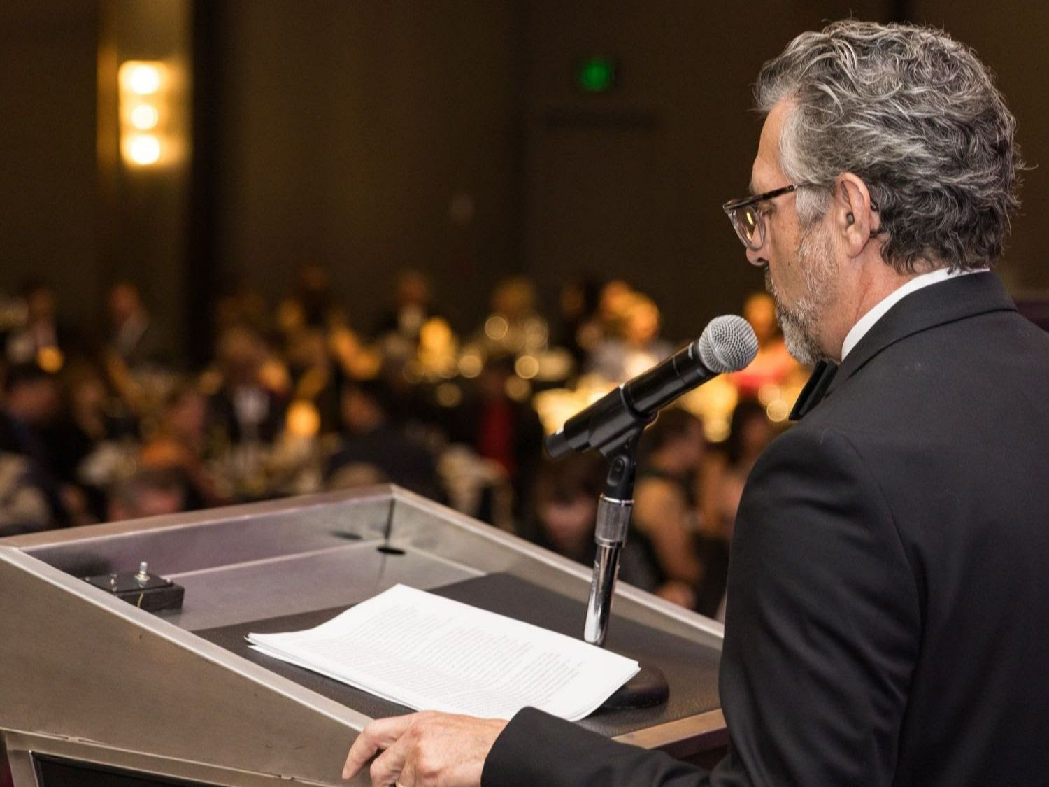 vincent standing at a podium with a microphone in front of a crowd