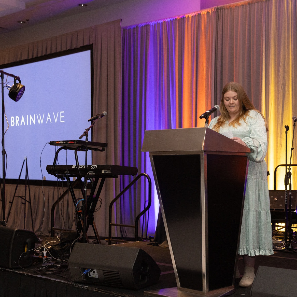 a woman standing at a podium in front of a microphone