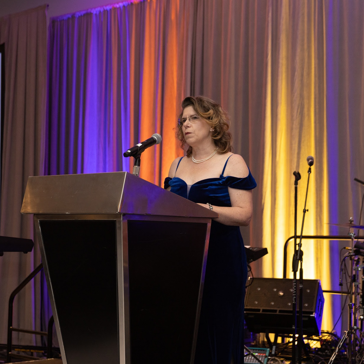 a woman standing at a podium in front of a microphone