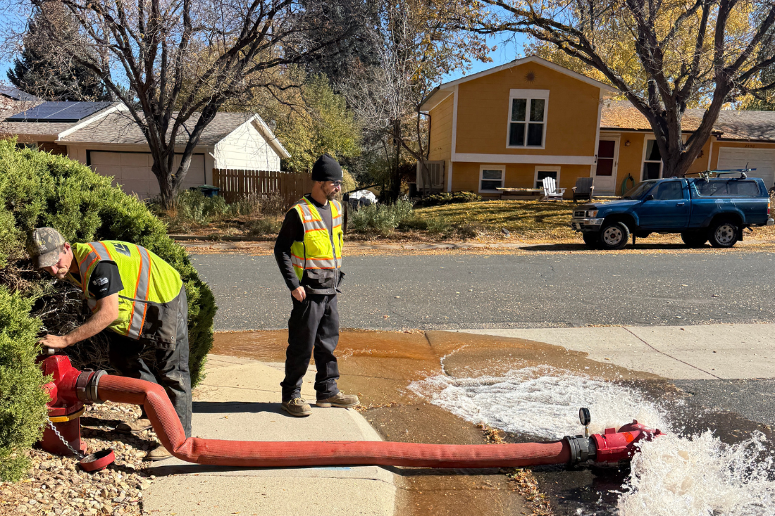 city worker in safety vest closing a hydrant with rushing out of it
