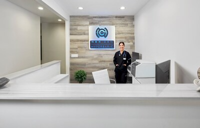 Interior view of the newly renovated front desk area at the NexGen Hyperbaric flagship facility in Naples, Florida, featuring a smiling individual and the prominently displayed NexGen Hyperbaric logo. Interior view of the newly renovated front desk area at the NexGen Hyperbaric flagship facility in Naples, Florida, featuring a smiling individual and the prominently displayed NexGen Hyperbaric logo.