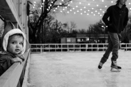 clack and white photo of toddler looking at ice rink