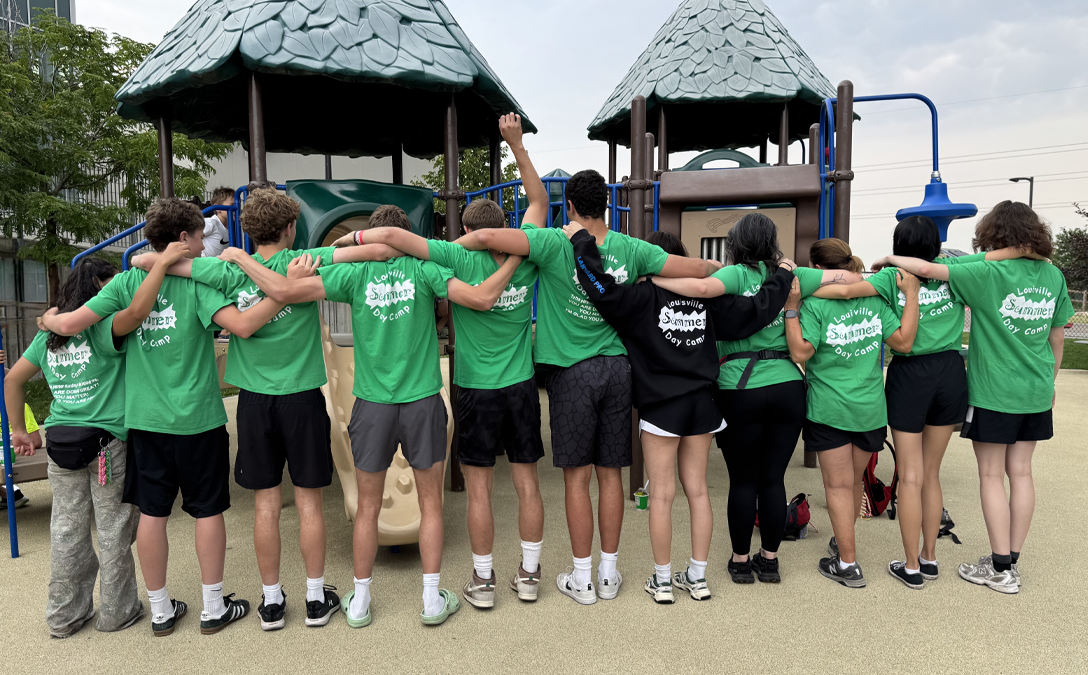 Summer Camp Counselors showing off the back of their shirts 