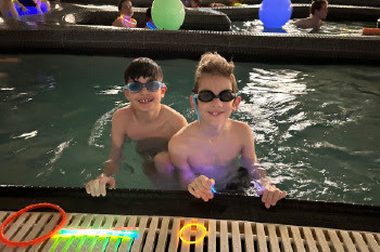 two kids swimming with glow sticks