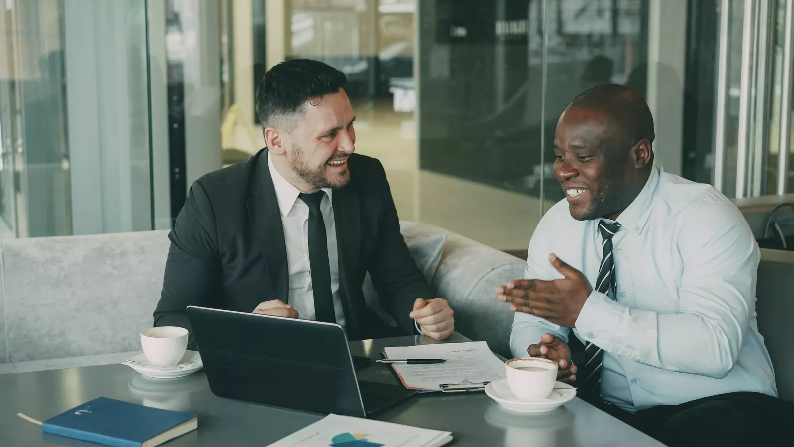 Two businessmen laughing during a meeting at a cafe.