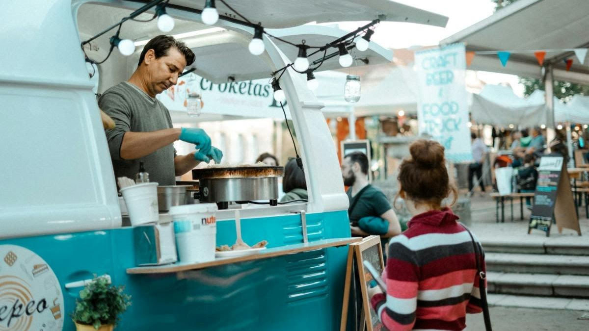 Man serving food to a woman from a food truck window