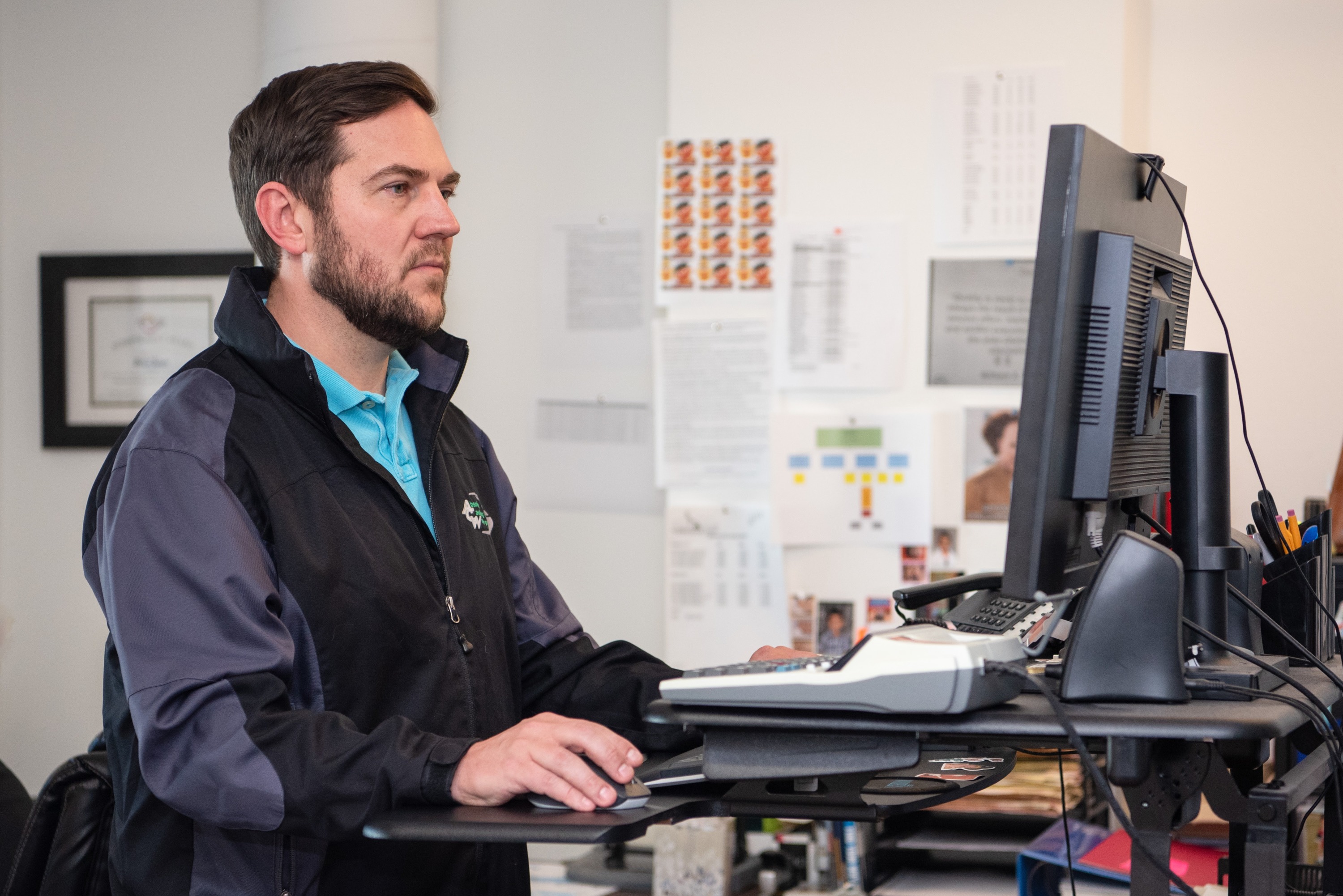 man with beard and blue shirt works at computer