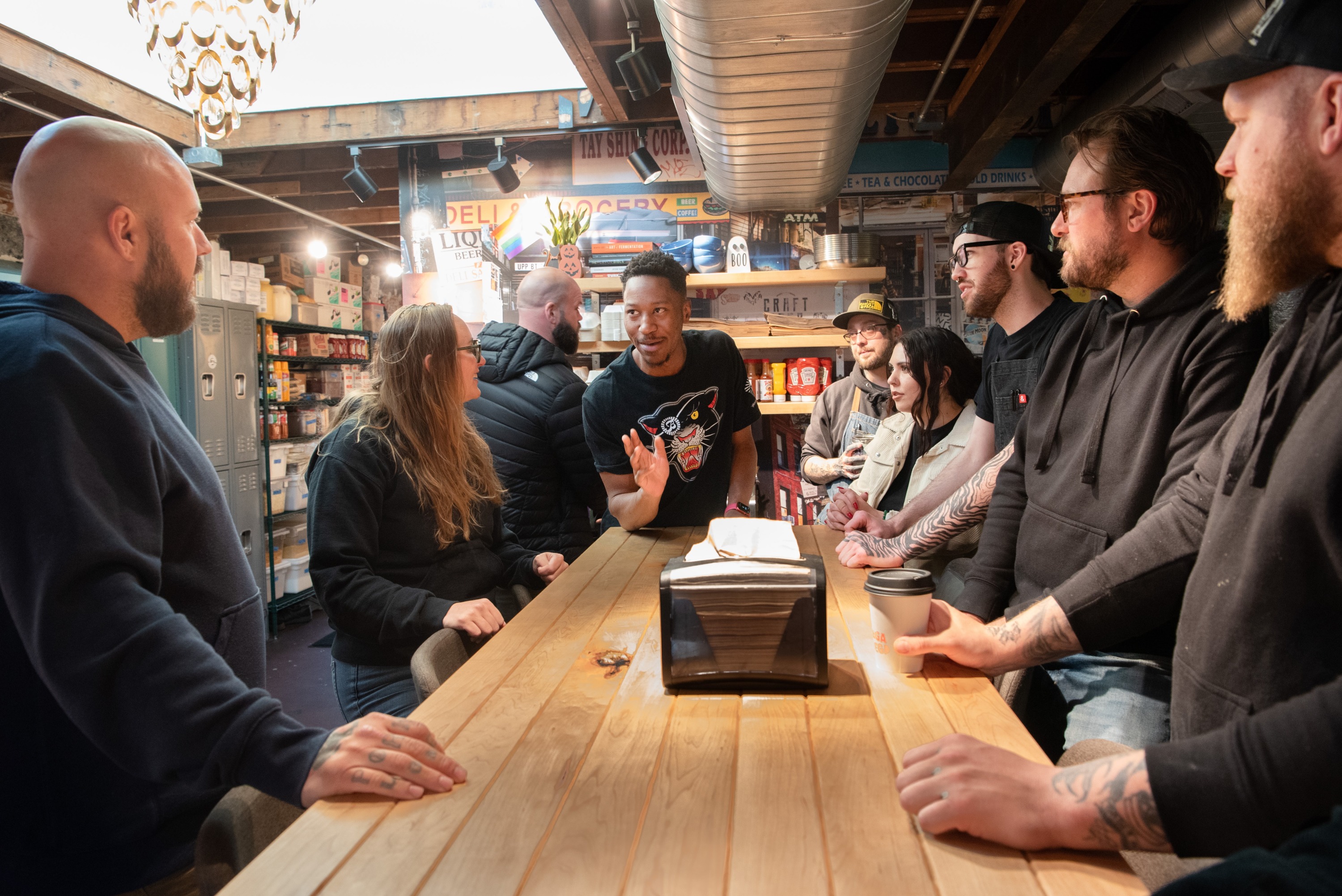 restaurant staff meet and talk around a wood counter