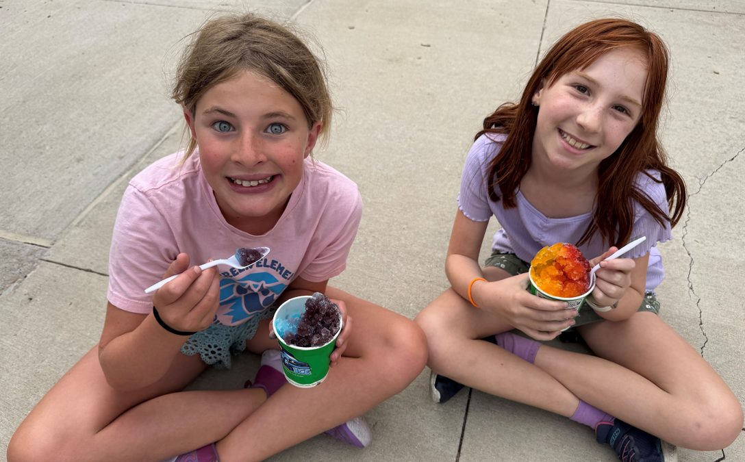 Two girls eating Kona Ice at summer camp