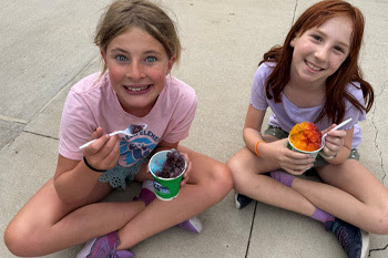 Two girls eating Kona Ice 