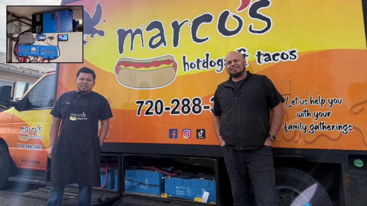 Two men stand in front of a food truck with the truck