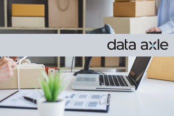 soft focus background image of small business working space with computer, barcode scanner, and packing supplies, with "data axel" logo