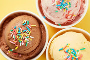 Scoops of vanilla, chocolate, and strawberry ice creams in separate cups, each topped with sprinkles