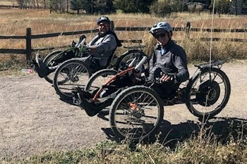 Two individuals on adaptive bicycles