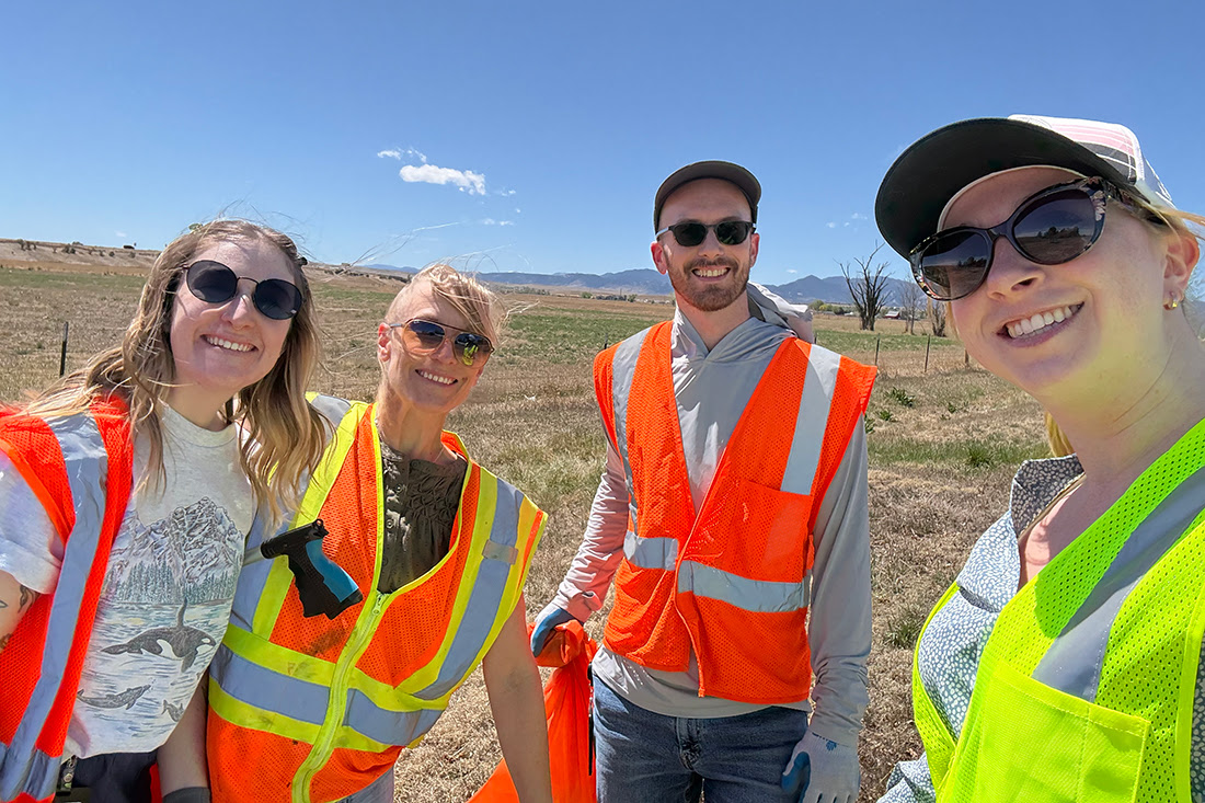 A group of four volunteers from Umoja Biopharma in orange safety vests during trash cleanup