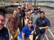 wastewater treatment team posing at the plant with their mascot, swirly (a poop emoji)