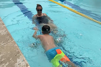 kid taking swim lessons at outdoor pool 
