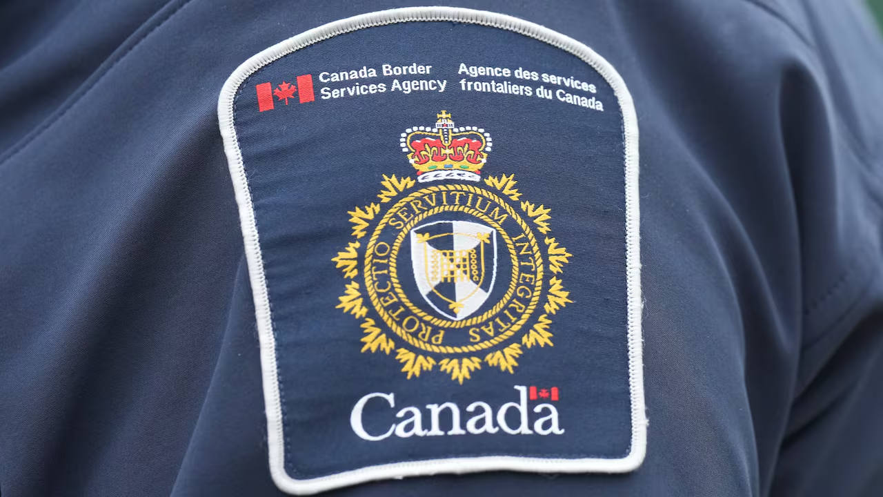 A Canadian Border Services patch appears on the shoulder of an officer wearing a dark blue uniform