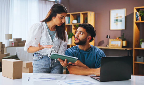 Two small business team members in the back office in discussion at computer