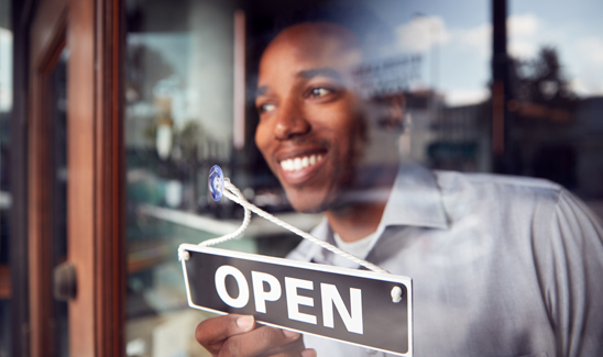 Small business owner flipping open sign on glass retail door