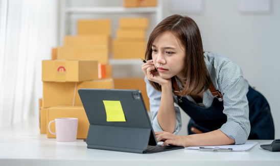 Business woman back office standing leaning over desk looking carefully at computer screen