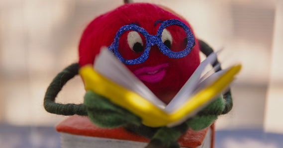 Fiber tomato with sparkly glasses reading a book