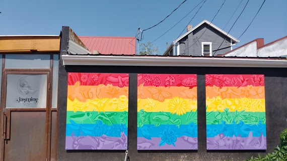 Three panel painted as the LGBTQ flag with Colorado flora and fauna incorporated in the design
