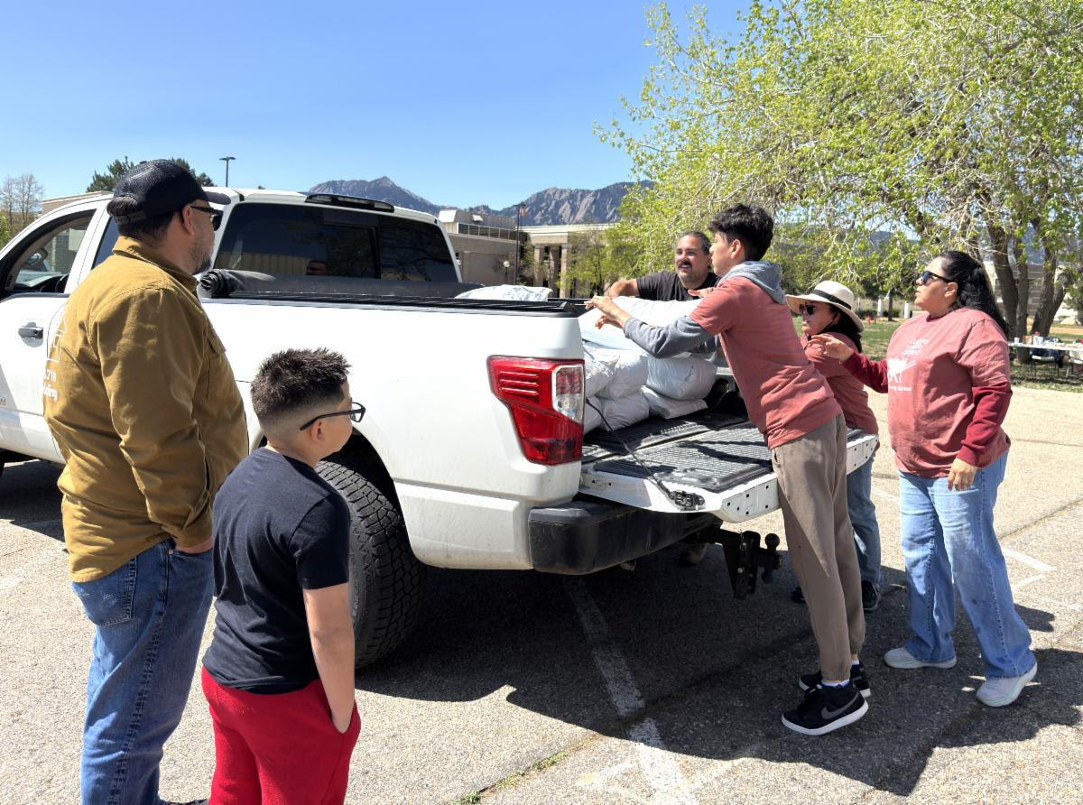 A family with parents, aunts and two boys loads soil into the back of a white pickup truck.