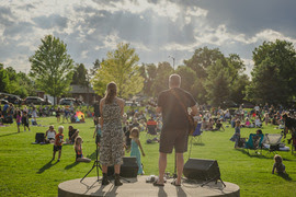 Two musicians glowing in the sun on the stage at community park