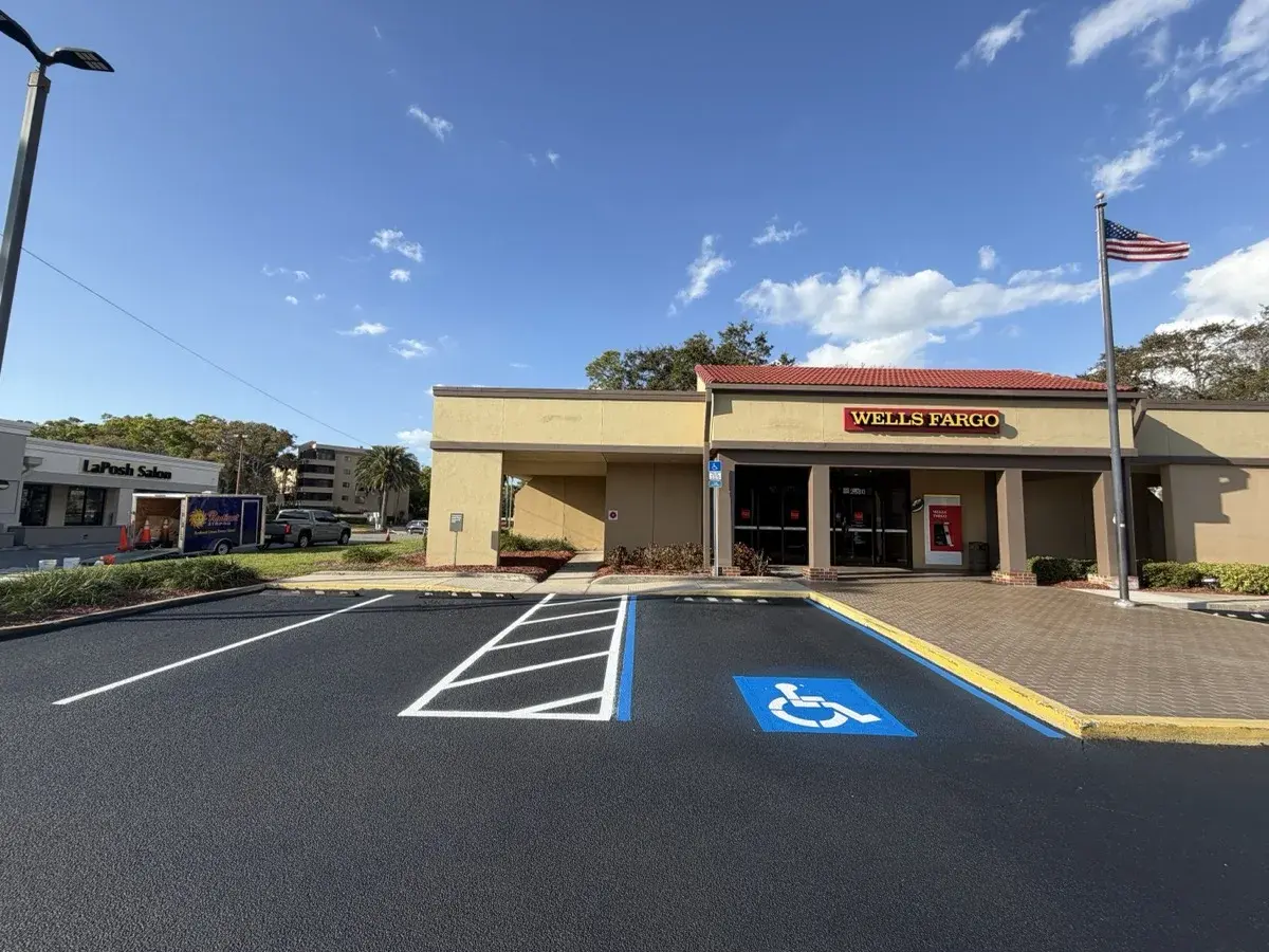 Freshly sealcoated Wells Fargo parking lot with new ADA accessible stalls by Radiant Striping in Tampa